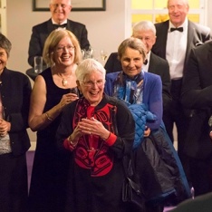 A group of people at an event laughing as they listen to a speech